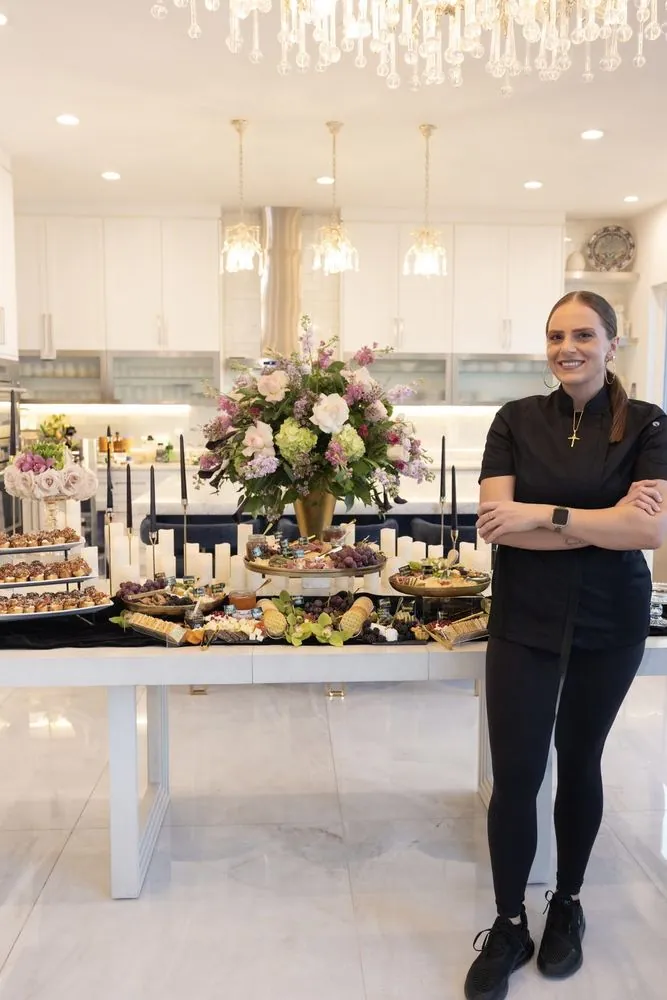 Chef Selena beside a styled grazing table under the chandeliers