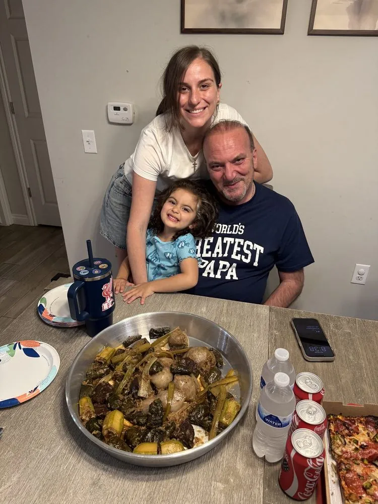 Family gathered around a big pan of home-cooked food
