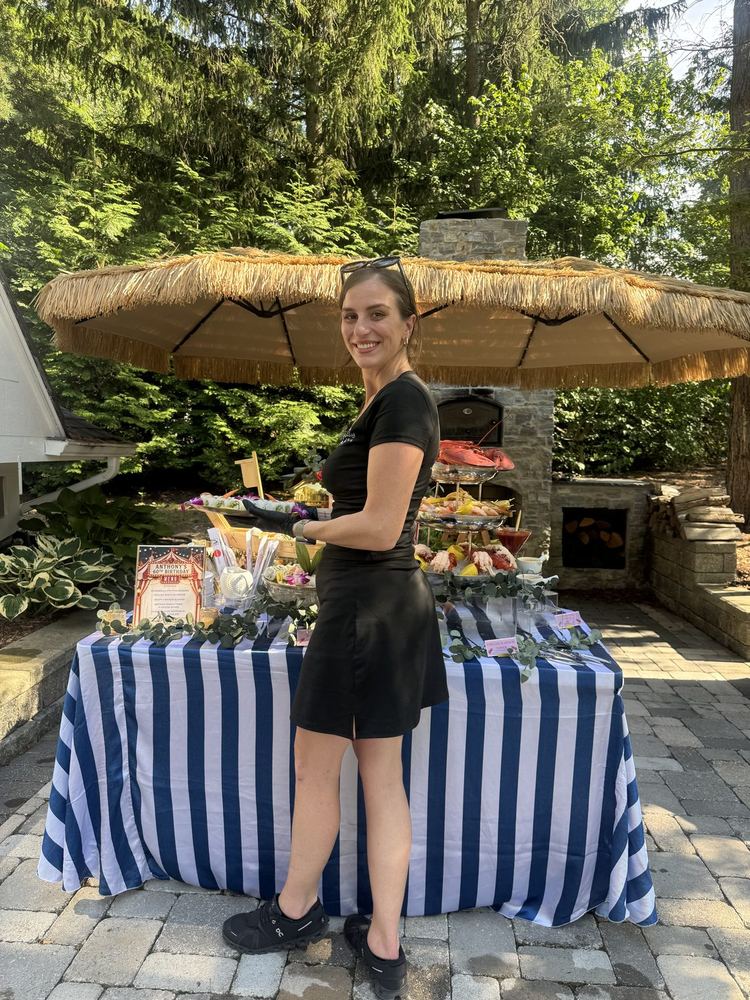 Mariah beside a styled outdoor buffet table dressed in navy stripes under a cabana