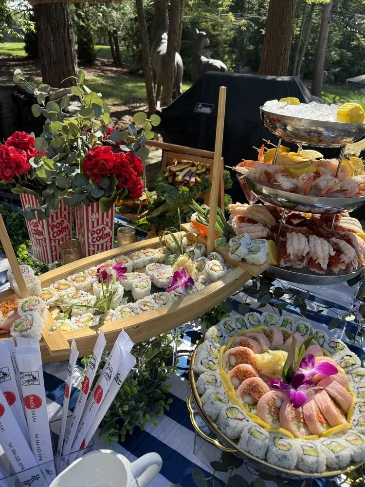 An outdoor sushi and dessert display styled with roses and tiered stands