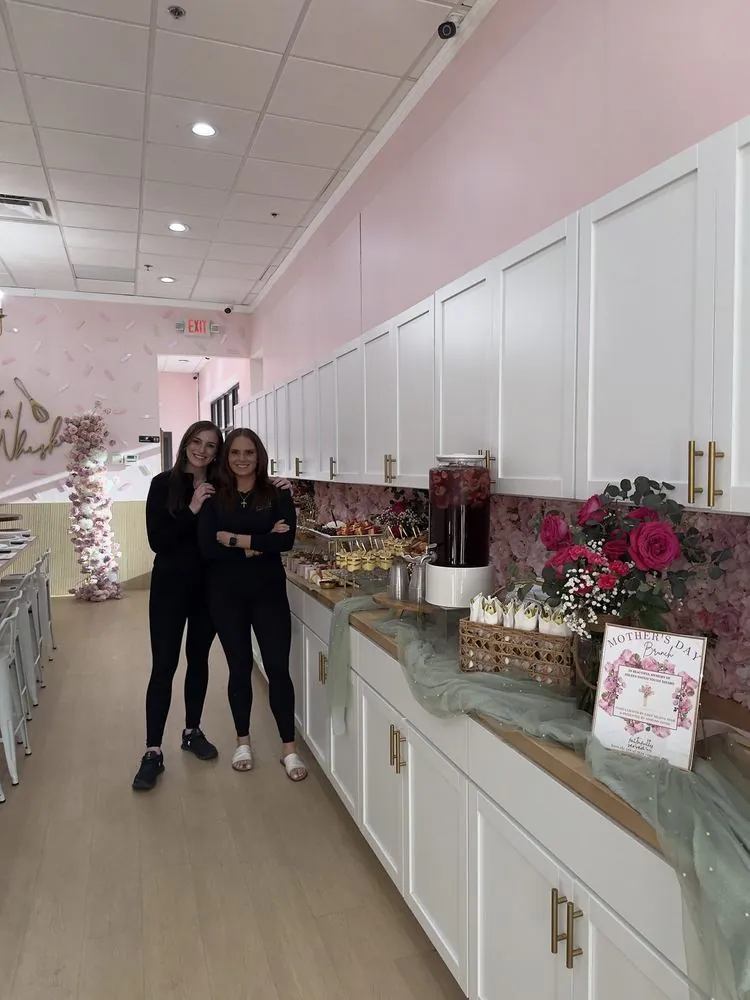 Mariah and Chef Selena beside a styled dessert counter in a blush-pink venue