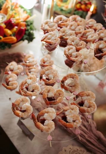 Chilled shrimp cocktail shooters lined up along a grazing table
