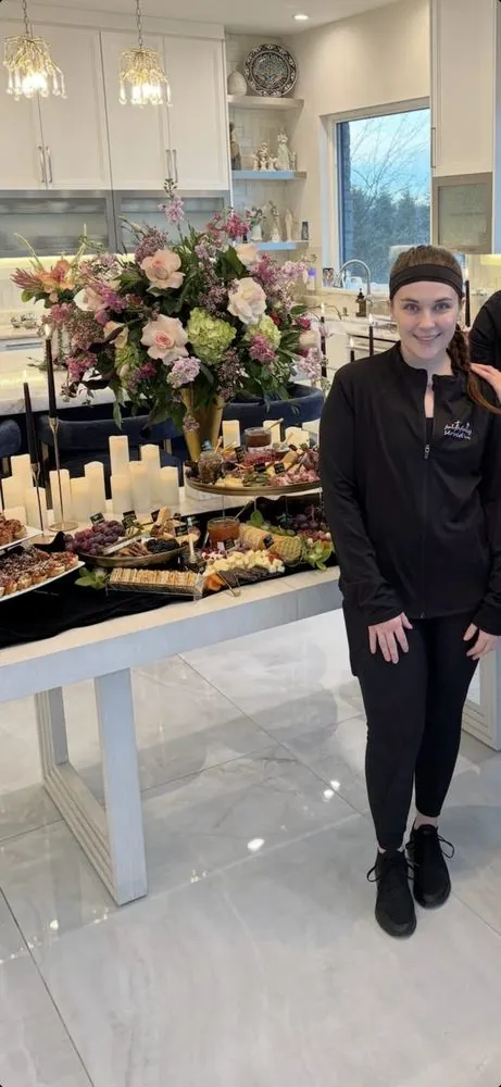 Sarah beside a styled charcuterie display of boards, candles, and florals
