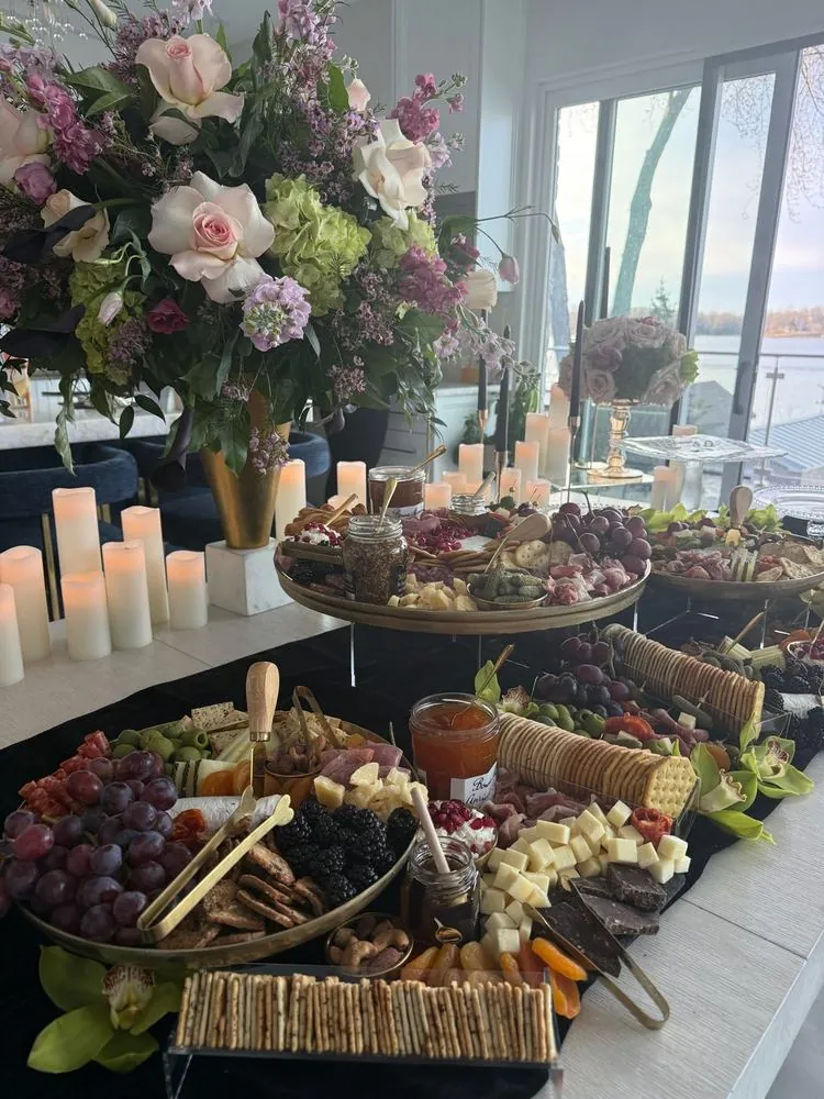 An abundant grazing spread of tiered boards, cheeses, fruit, and florals
