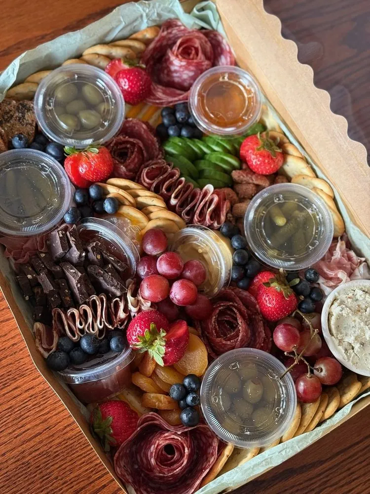 A charcuterie box of salami roses, berries, olives, dips, and crackers